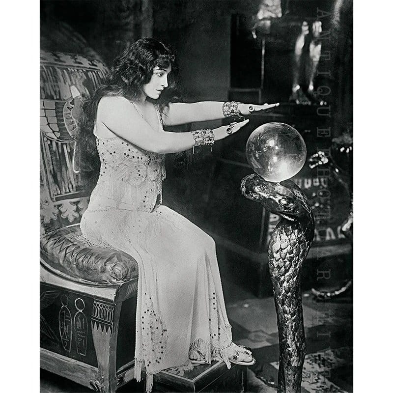 Woman seated in a trance with hands over crystal ball - Handy Entertainment